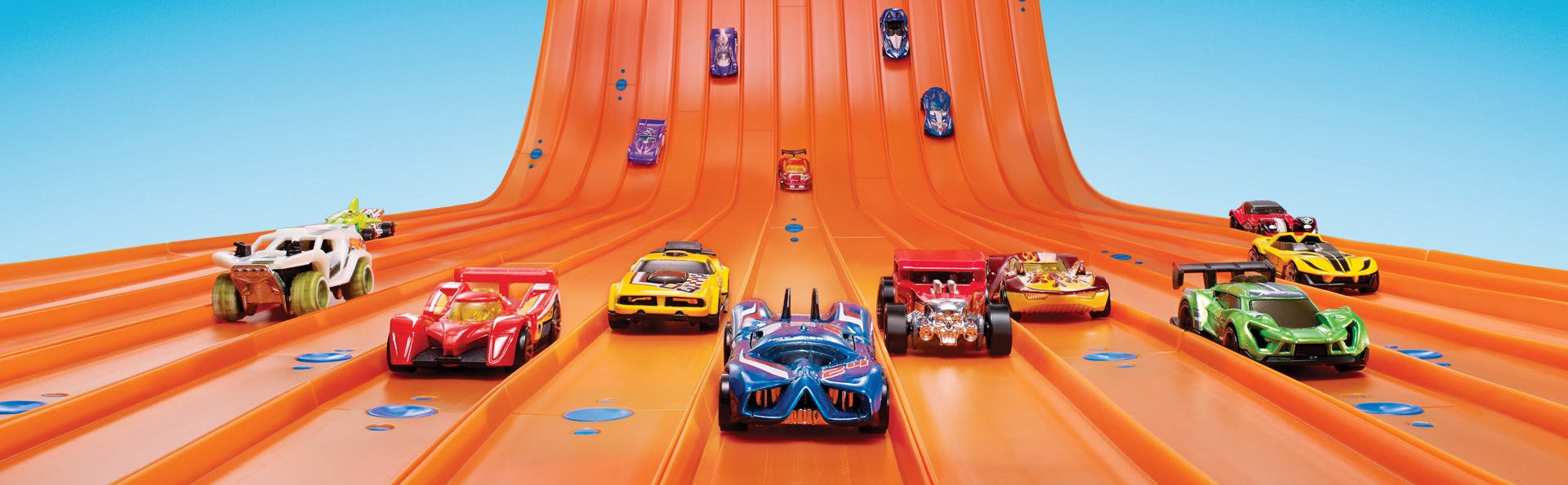 Toy cars on an orange track with a blue sky background